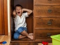 Little boy hiding in a cupboard and crying Royalty Free Stock Photo