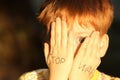 Little boy hiding face and words Stop War written on his hands outdoors, closeup Royalty Free Stock Photo