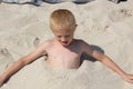 Little boy hiding himself in sand on the beach Royalty Free Stock Photo