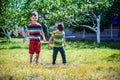 Little boy and his brother play in summer park. Children with colorful clothes jump in puddle and mud in the garden