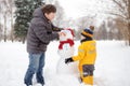 Little boy with his father building snowman in snowy park. Active outdoors leisure with children in winter Royalty Free Stock Photo