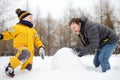 Little boy with his father building snowman in snowy park. Active outdoors leisure with children in winter Royalty Free Stock Photo