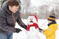 Little boy with his father building snowman in snowy park. Active outdoors leisure with children in winter Royalty Free Stock Photo