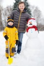 Little boy with his father building snowman in snowy park. Active outdoors leisure with children in winter Royalty Free Stock Photo