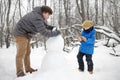 Little boy with his father building snowman in snowy park. Active outdoors leisure with children in winter. Kid during stroll in a Royalty Free Stock Photo