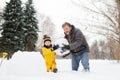 Little boy with his father building snowman in snowy park. Active outdoors leisure with children in winter Royalty Free Stock Photo