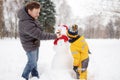 Little boy with his father building snowman in snowy park. Active outdoors leisure with children in winter Royalty Free Stock Photo