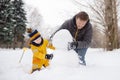 Little boy with his father building snowman in snowy park. Active outdoors leisure with children in winter Royalty Free Stock Photo