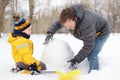 Little boy with his father building snowman in snowy park. Active outdoors leisure with children in winter Royalty Free Stock Photo