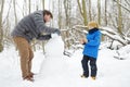 Little boy with his father building snowman in snowy park. Active outdoors leisure with family with children in winter. Stroll in Royalty Free Stock Photo