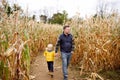 Little boy and his father having fun on pumpkin fair at autumn. Family walking among the dried corn stalks in a corn maze. Royalty Free Stock Photo