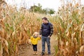 Little boy and his father having fun on pumpkin fair at autumn. Family walking among the dried corn stalks in a corn maze. Royalty Free Stock Photo