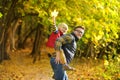 Little boy and his father having fun during stroll in the forest on sunny autumn day. The father rides the child on own back. Royalty Free Stock Photo