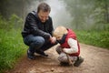 Little boy and his father looking on big snail during hike in forest. Royalty Free Stock Photo