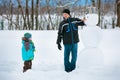 Little boy with his father making a snowman