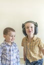 A little boy with his headphones dances with his brother. Two little brothers in shirts amuse themselves and dance. Royalty Free Stock Photo