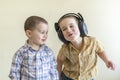 A little boy with his headphones dances with his brother. Two little brothers in shirts amuse themselves and dance. Royalty Free Stock Photo