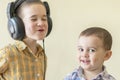 A little boy with his headphones dances with his brother. Two little brothers in shirts amuse themselves and dance. Royalty Free Stock Photo