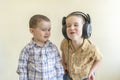 A little boy with his headphones dances with his brother. Two little brothers in shirts amuse themselves and dance. Royalty Free Stock Photo