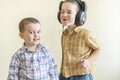 A little boy with his headphones dances with his brother. Two little brothers in shirts amuse themselves and dance. Two Royalty Free Stock Photo