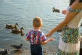 A little boy and his mom feed birds on the lake