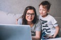 Little boy and his mother in video conference with teacher on laptop at home.