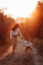 Little boy and his mother walking in the autumn park. Beauriful sunset time, red leaves Royalty Free Stock Photo