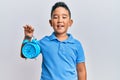 Little boy hispanic kid holding alarm clock looking positive and happy standing and smiling with a confident smile showing teeth Royalty Free Stock Photo