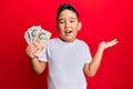 Little boy hispanic kid holding 10 united kingdom pounds banknotes celebrating achievement with happy smile and winner expression