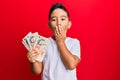 Little boy hispanic kid holding 10 united kingdom pounds banknotes covering mouth with hand, shocked and afraid for mistake Royalty Free Stock Photo