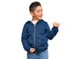 Little boy hispanic kid wearing casual sporty jacket smiling with happy face looking and pointing to the side with thumb up Royalty Free Stock Photo
