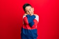 Little boy hispanic kid wearing casual winter sweater hugging oneself happy and positive, smiling confident Royalty Free Stock Photo