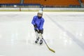 Little boy hockey player in blaue uniform posing with a hockey stick on ice hockey rink. Sport for children Royalty Free Stock Photo