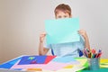 Little boy holding blank empty colored paper sheet covered face.