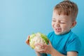 Little Boy Holding Broccoli in his hands on blue background, diet and exercise for good health concept Royalty Free Stock Photo