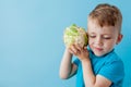 Little Boy Holding Broccoli in his hands on blue background, diet and exercise for good health concept Royalty Free Stock Photo