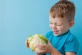 Little Boy Holding Broccoli in his hands on blue background, diet and exercise for good health concept Royalty Free Stock Photo