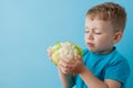 Little Boy Holding Broccoli in his hands on blue background, diet and exercise for good health concept Royalty Free Stock Photo