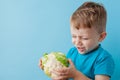 Little Boy Holding Broccoli in his hands on blue background, diet and exercise for good health concept Royalty Free Stock Photo