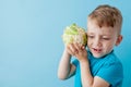 Little Boy Holding Broccoli in his hands on blue background, diet and exercise for good health concept Royalty Free Stock Photo