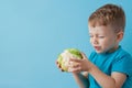 Little Boy Holding Broccoli in his hands on blue background, diet and exercise for good health concept Royalty Free Stock Photo