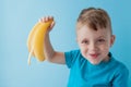 Little Boy Holding and eating an Banana on blue background, food, diet and healthy eating concept Royalty Free Stock Photo
