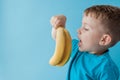 Little Boy Holding and eating an Banana on blue background, food, diet and healthy eating concept Royalty Free Stock Photo