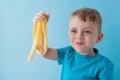 Little Boy Holding and eating an Banana on blue background, food, diet and healthy eating concept Royalty Free Stock Photo