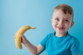 Little Boy Holding and eating an Banana on blue background, food, diet and healthy eating concept Royalty Free Stock Photo