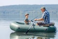 grandfather with grandson together fishing from inflatable boat Royalty Free Stock Photo