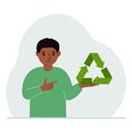 A little boy is holding a green recycle, recycling or ecology sign in his hands.