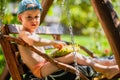 Little boy holding ripe sunflower head. Cute little boy in a baseball cap sits on a swing Royalty Free Stock Photo