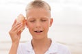 Little boy holding a seashell close to his ear Royalty Free Stock Photo