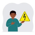 A little boy is holding a yellow warning sign with a black lightning in his hand. The concept of the danger of electric Royalty Free Stock Photo